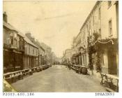 Sepia photograph showing view looking west along London Street, Basingstoke, street is lined with tables and benches, many supported by barrels, flags and bunting adorn the buildings, decorated to celebrate the Diamond Jubilee of Queen Victoria in June 