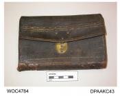 Wallet, pocket book, man's, black leather embossed in gold Wm Attwood, Basingstoke, Hants, 1763, front face with decorative brass hoook and oval brass plate with central line of four pierced holes, lined chestnut leather with embossed detail, four inter