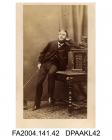 Photograph, Sir Alfred Tichborne, half seated on a table and leaning against a small cabinet, taken by Heath and Beau of Londonvol 1, page 7 - Relatives and Friends