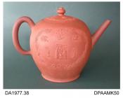 Punch pot, or teapot, red stoneware, inverted pear shape, applied sprigs of exotic birds and chinoiserie figures - one possibly showing the making and consumption of hot punch - within a rococo border, pseudo-Chinese seal mark on base, made in Staffords