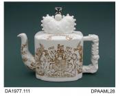 Teapot, white earthenware, rectangular shape with coved corners and lid in the form of a crown surmounted by a silver lustred cross, printed decoration consisting of the Royal arms and national emblems, printed factory and silver lustre painted piece ma