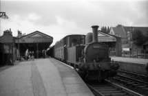 Digital image copy at 800 dpi of an original black and white print photograph retained by donor of Mike Peart, showing a B4 class shunting locomotive, 30102 can be seen attaching parcels van to the rear of the train at Winchester City Station. Image one of two.