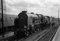 Digital image copy at 800 dpi of an original black and white print photograph retained by donor of Mike Peart, showing a Lord Nelson class 30857 "LORD HOWE" getting a footplate crew change at Eastleigh Station.
