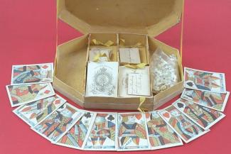 Card game, octagonal cardboard box with hinged lid decorated with a floral design and 6 compartments, containing 2 packs of colour printed playing cards with full length court cards and square corners, 1 pack made by Reynolds and Son and the other by Ha