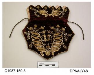 Bag, or reticule, plum coloured velvet, hexagonal with dentate upper edge to cuff, decorated with gold, cut steel and pearl beading, all outer edges trimmed gold and pearl beading, bag lined plum silk, cuff lined pale pink satin, drawstring closure of f