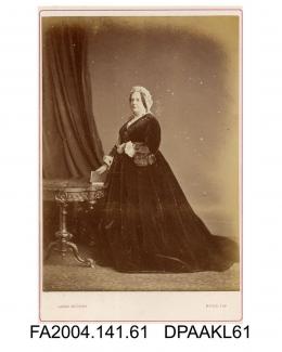 Photograph, The Honourable Dowager Lady Arundell standing by table, book in hand, taken by Jabez Hughes of Ryde, Isle of Wight, circa 1868-9vol 1, page 9