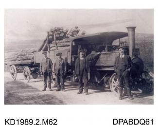 Photograph, black and white, showing four men with a trailer loaded with logs and a steam wagon, built by Tasker and Co, Waterloo Foundry, Anna Valley, Abbotts Ann, Hampshire