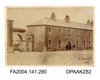 Photograph, the main entrance and the Officers Quarters at Cahir Barracks with men grouped around the doorway, taken by R Vervega, 1869vol 1, page 35